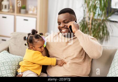 padre con il bambino a casa che chiama con lo smartphone Foto Stock