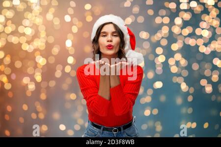 felice giovane donna a santa hat che invia bacio d'aria Foto Stock