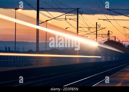 Ferrovia all'alba. Sentieri leggeri del treno passeggeri alla stazione ferroviaria. Foto Stock