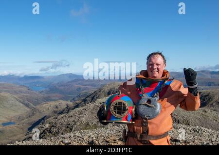 Il veterano Lloyd Scott, che sta tentando di scalare le tre vette in aiuto della beneficenza Lord's Taverners mentre indossa una tuta per immersioni in alto mare, sulla cima dello Scafell Pike, nel Lake District National Park, in Cumbria. Foto Stock