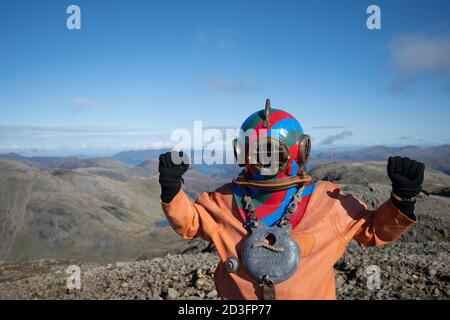 Il veterano Lloyd Scott, che sta tentando di scalare le tre vette in aiuto della beneficenza Lord's Taverners mentre indossa una tuta per immersioni in alto mare, sulla cima dello Scafell Pike, nel Lake District National Park, in Cumbria. Foto Stock