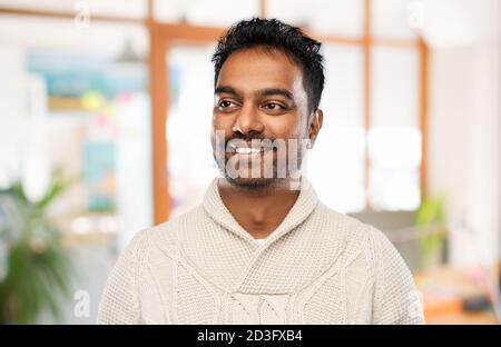indiano uomo in maglione su sfondo ufficio Foto Stock