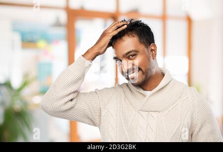 Indian uomo in felpa lavorata a maglia di toccare i suoi capelli Foto Stock