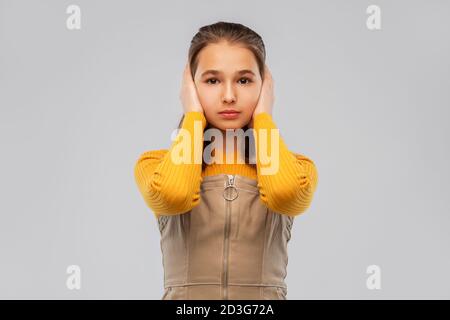 sorridente ragazza adolescente che chiude le orecchie con le mani Foto Stock