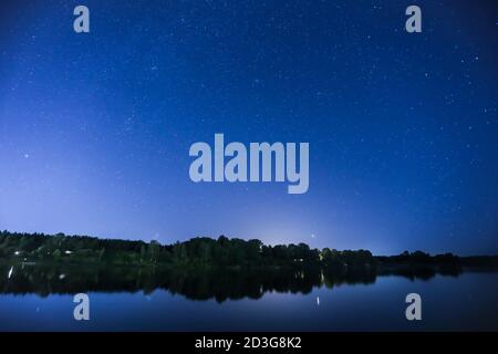 Cielo notturno con stelle. Via Lattea in un cielo di fronte al grande fiume. Fotografia di paesaggio. Foto Stock