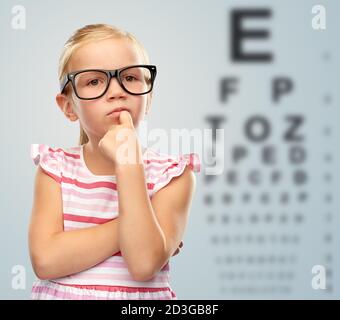 bambina in occhiali sopra la tabella di prova dell'occhio Foto Stock