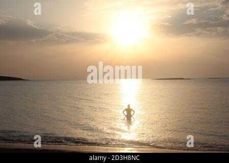 Un uomo gioca al Tramonto a Panagia Beach nell'isola di Elafonisos, nella parte meridionale del Peloponneso, in Grecia Foto Stock