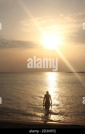 Un uomo gioca al Tramonto a Panagia Beach nell'isola di Elafonisos, nella parte meridionale del Peloponneso, in Grecia Foto Stock