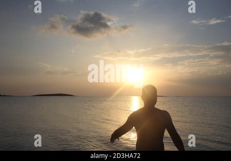 Un uomo gioca al Tramonto a Panagia Beach nell'isola di Elafonisos, nella parte meridionale del Peloponneso, in Grecia Foto Stock