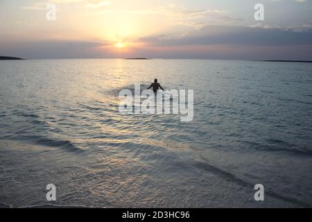 Un uomo gioca al Tramonto a Panagia Beach nell'isola di Elafonisos, nella parte meridionale del Peloponneso, in Grecia Foto Stock