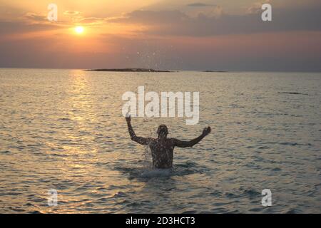 Un uomo gioca al Tramonto a Panagia Beach nell'isola di Elafonisos, nella parte meridionale del Peloponneso, in Grecia Foto Stock