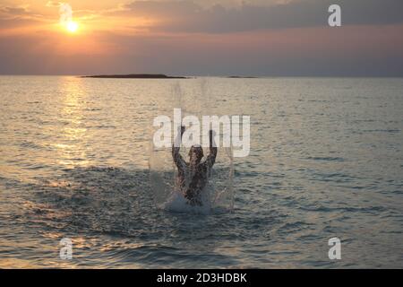 Un uomo gioca al Tramonto a Panagia Beach nell'isola di Elafonisos, nella parte meridionale del Peloponneso, in Grecia Foto Stock