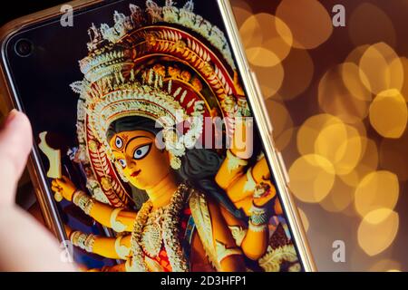 Felice Durga Puja sfondo. Persona che scorre o visualizza le immagini Durga Puja sul telefono cellulare. Festa religiosa indù indiana festa in casa duri Foto Stock