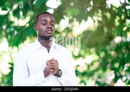 L'uomo africano che prega per ringraziare dio nella natura verde Foto Stock