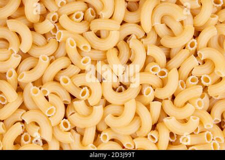 Uno sfondo di un primo piano di una piastra di maccheroni grezzi a gomito Foto Stock