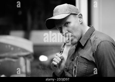 Uomo maturo di fumare sigarette elettroniche per le strade di notte Foto Stock