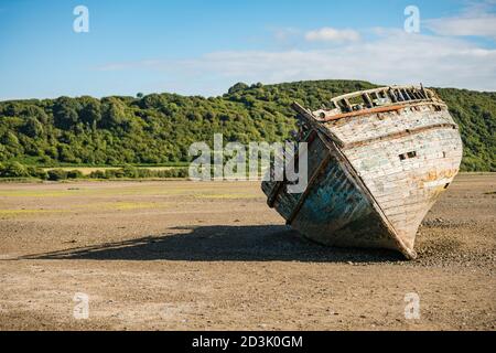 Barca di legno abbandonata che lentamente decadendo su Traeth Dulas, Anglesey, Galles Foto Stock