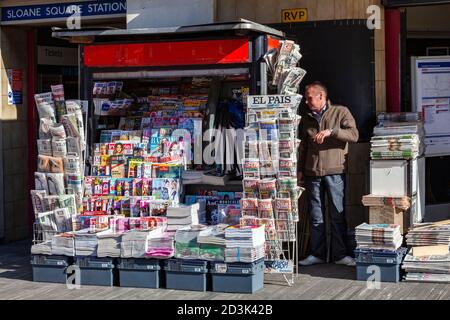 Londra, UK, 26 Febbraio 2012 : Venditore che vende giornali e riviste inglesi e straniere presso uno stand di edicola fuori dalla stazione della metropolitana di Sloane Square Foto Stock