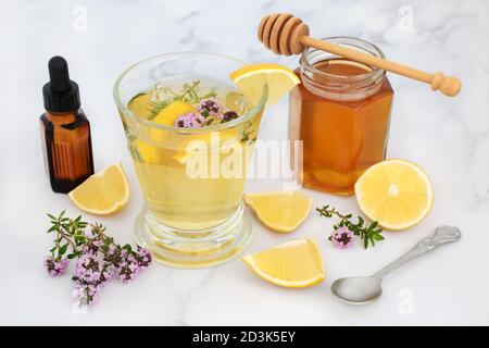 Rimedio medicinale alternativo per il virus del raffreddore e dell'influenza con erbe al timo, miele e limone in vetro con olio essenziale. Farmaci immunostimici. Foto Stock