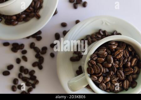 Chicchi di caffè in tazza, su sfondo bianco isolato.Vista dall'alto.sfondo creativo. Foto Stock