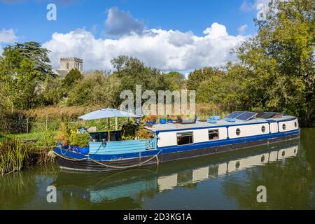 Narrowboat ormeggiato sulla riva del ramo Bruce del Kennett e Avon Canal con vista sulla chiesa di St Mary, Great Bedwyn, un villaggio nel Wiltshire, Regno Unito Foto Stock