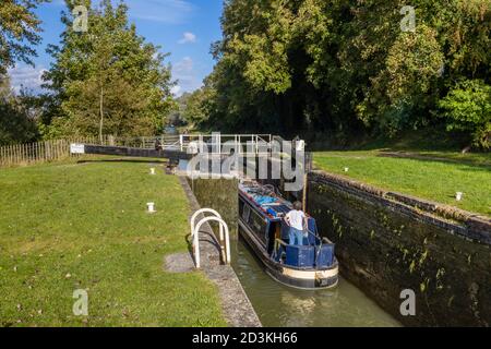 Narrowboat passando attraverso un blocco sul ramo Bruce del Kennett e Avon Canal a Great Bedwyn, un villaggio nel Wiltshire orientale, Inghilterra meridionale Foto Stock