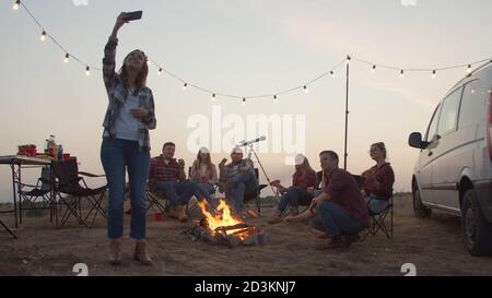 Giovane donna che prende selfie con gli amici durante il picnic Foto Stock