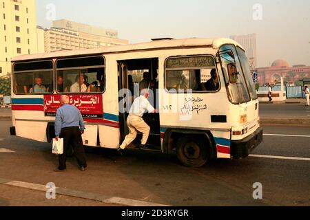 Vista sulla strada al Cairo. Un uomo salta su un autobus in movimento nel centro della città Foto Stock