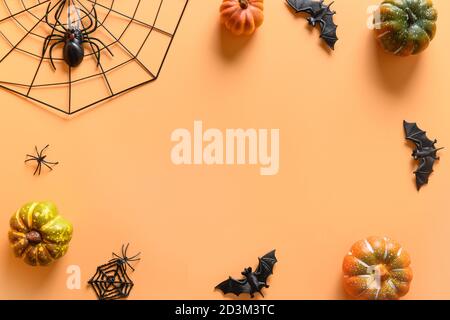 Halloween cornice di divertenti decorazioni partito, zucche, web spooky, pipistrelli, ragno su sfondo arancione. Vista dall'alto, disposizione piatta. Spazio di copia. Foto Stock