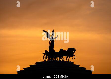 Statua della Dea Victoria a cavallo su quadriga sulla sommità del monumento a Vittorio Emanuele II al tramonto, Roma, Italia Foto Stock