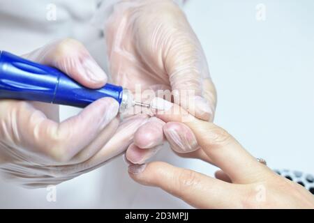 Salone di bellezza, manicure, procedura di Nail Polish. Manicure hardware professionale che utilizza una macchina elettrica nel servizio chiodi. Persona irriconoscibile usa una macchina elettrica durante il manicure. Foto Stock