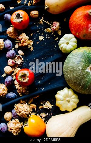 Fondo alimentare autunnale, con mele, persimmons, zucche, noci con fiori secchi, immagine concettuale per il cambio di stagione. Foto Stock