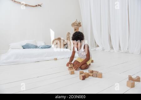 Little Happy boy African American giocare case con ecmattoni di legno, costruire e distruggere torri. Fine sviluppo motori, giochi educativi. Bianco inter Foto Stock