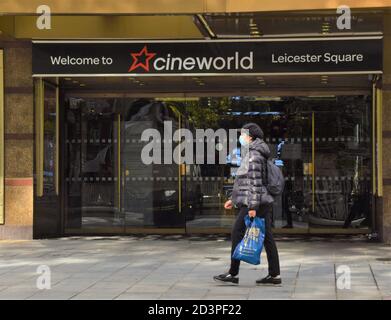 Una donna con una maschera protettiva passa davanti al Cineworld Empire Cinema a Leicester Square, Londra Foto Stock