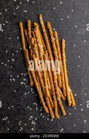 Bastoncini salati. Pretzel croccanti con semi di sesamo su tavola nera. Vista dall'alto. Foto Stock