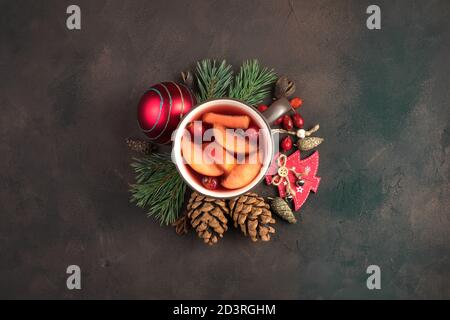 Bella composizione natalizia con una tazza di VIN brulé circondata da decorazioni natalizie su fondo di cemento marrone. Sfondo delle vacanze. Foto Stock