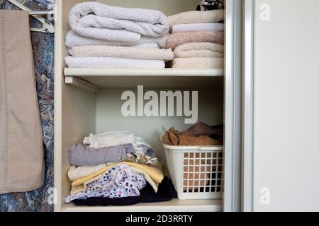 armadio completo con vestiti e pila di asciugamani in bianco armadio di legno, organizzazione e deposito Foto Stock