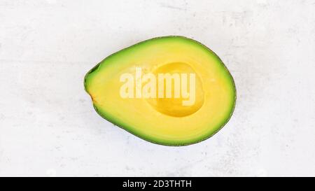 Mezzo avocado, con polpa gialla brillante su tavola di pietra bianca, foto dall'alto Foto Stock