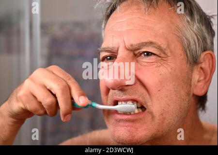 Uomo anziano in bagno con l'uso di una spazzola a denti Foto Stock