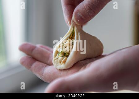 Una delle fasi di produzione di gnocchi di carne - sopra la tavola su un pezzo di impasto è una carne ripieno di verde accanto ad un cumulo di farina Foto Stock