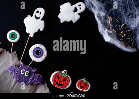 Flatlay di pan di zenzero dipinto per Halloween. Cibo per bambini. Decorazioni per il tavolo festivo: Fantasmi, pipistrelli, occhi spaventosi, ciottoli, zucche. Copia Foto Stock