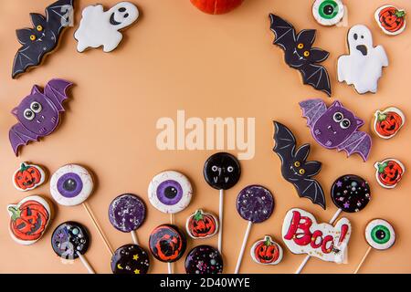 Halloween pan di zenzero piatto su sfondo arancione isolato. Il cibo per bambini è un piacere per la vacanza. Lollipop fatti a mano, biscotti fantasma, zucche, Foto Stock