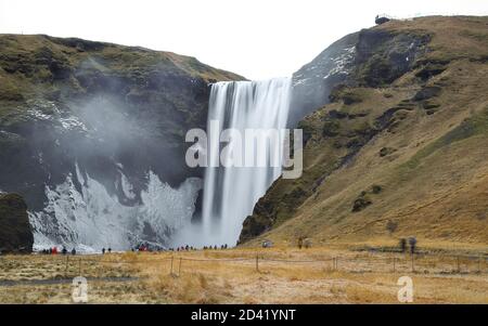 SKOGA, ISLANDA - 10 dicembre 2018: Molti turisti visitano Skogafoss, una delle cascate più popolari dell'Islanda. Foto Stock