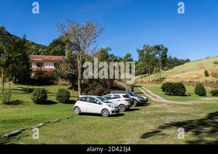 Le auto parcheggiate su un campo di erba verde fuori dalla fabbrica di birra Wolkenburg si trovano nella campagna di Cunha e sotto il cielo blu tardo pomeriggio. Foto Stock