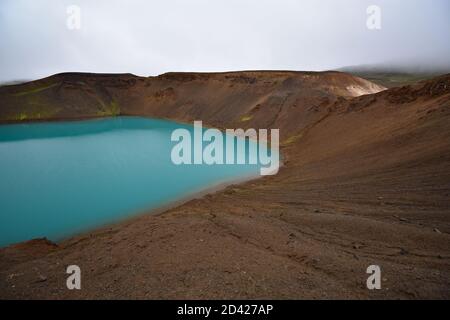 Il lago verde blu all'interno del cratere Krafla viti nell'area del Lago Myvatn nel Nord dell'Islanda su uno sfondo di nuvole bianche. Foto Stock