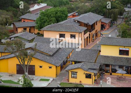 villaggio con diverse piccole case gialle e rosa con tetto di tegole nere, alberi tra le case Foto Stock