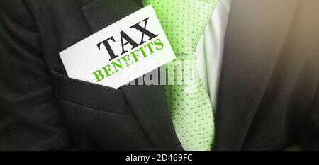 Uomo d'affari mantiene una carta con testo benefici fiscali nella tasca superiore del suo vestito. Concetto di tasse e tasse Foto Stock