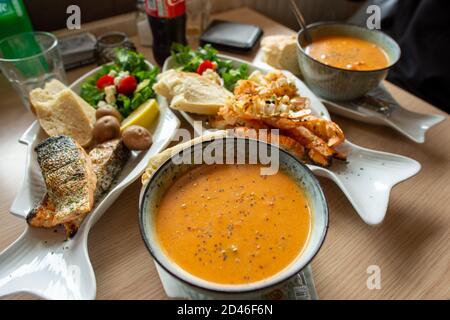 Zuppa di langostina e Langoustine grigliate con salle su un piatto a forma di pesce bianco. Impostare bei pane e verdure sul tavolo da pranzo. A riposo Foto Stock