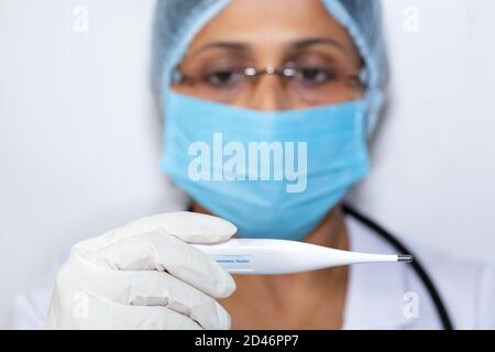 Medico femminile indiano che controlla la temperatura corporea del paziente utilizzando un termometro digitale Foto Stock