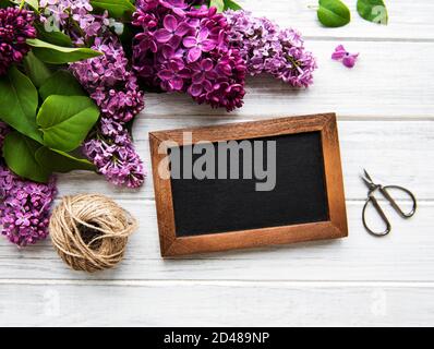 Fiori lilla freschi cornice su sfondo di legno con spazio copia su lavagna, piatto composizione floreale Foto Stock
